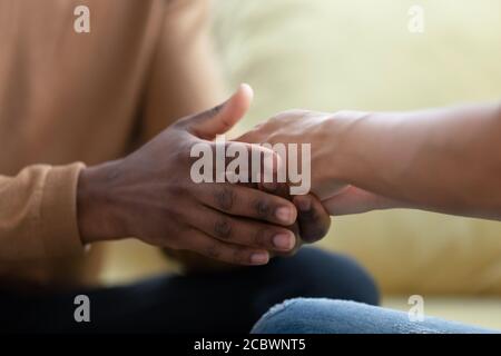 Marito africano che tiene le mani della moglie biraciale con cura e amore Foto Stock