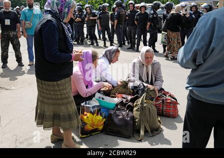 Donne affamate che si siedono su un marciapiede e mangiano, poliziotti che guardano sullo sfondo. 25 maggio 2013. Kiev, Ucraina Foto Stock