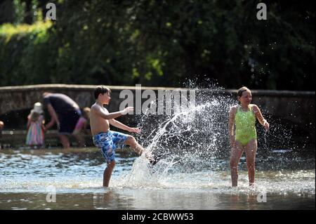 L'ondata di caldo continua nelle Cotswolds, dove le temperature sono salite a. 33 gradi e la folla impaccavano i verdi di erba al Lato del fiume Windrush i Foto Stock