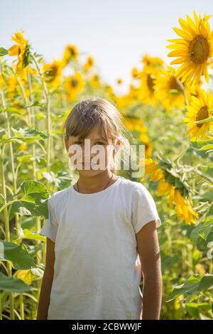 Una giovane ragazza adolescente si trova in un campo circondato da girasoli Foto Stock