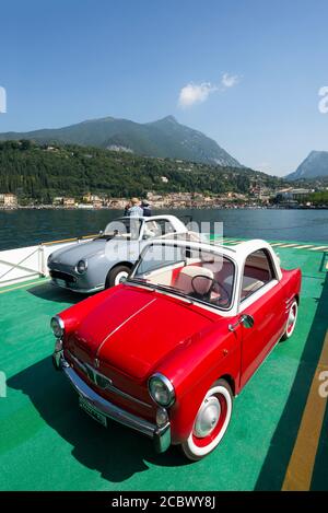 Una classica Autobianchi Bianchina Trasformabile rossa e una Cabriolet Nissan Figaro grigia sul ponte di un traghetto sul Lago di Garda Foto Stock