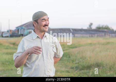 Un uomo musulmano anziano sta in piedi e sta parlando di qualcosa di divertente. Foto Stock