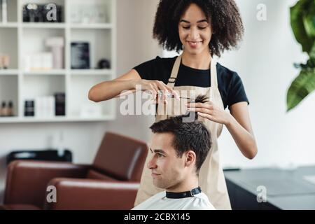 Giovane uomo che ottiene i suoi capelli tagliati al salone dei parrucchieri Foto Stock