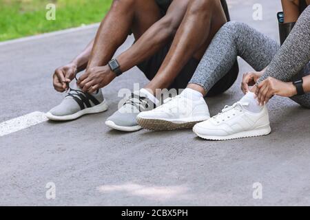 Coppia di corridori neri stringono le loro scarpe all'aperto, preparandosi per fare jogging Foto Stock