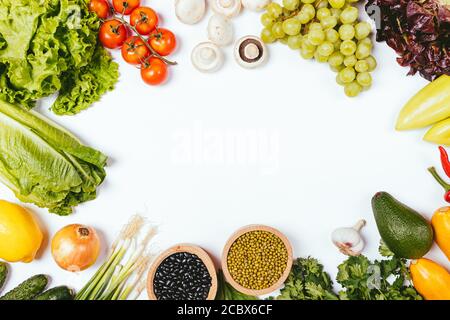 Sano stile di vita cibo sfondo da verdure fresche, erbe, frutta e fagioli su tavola bianca, piatto telaio. Foto Stock