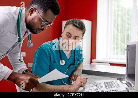 i chirurghi veterinari stanno esaminando una radiografia di un cane guardando la carta, discutendo le soluzioni al problema, come trattare Foto Stock