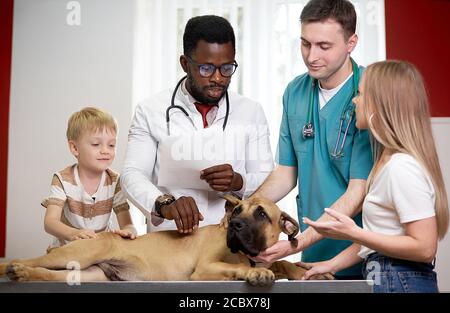 famiglia con il cane è venuto a controllare per l'esame annuale, donna di controllo. e figlio sono preoccupati per la salute del loro cane Foto Stock
