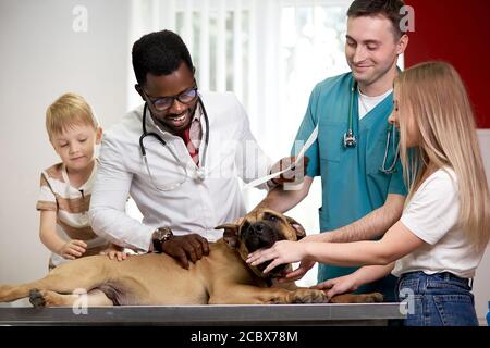 famiglia con il cane è venuto a controllare per l'esame annuale, donna di controllo. e figlio sono preoccupati per la salute del loro cane Foto Stock