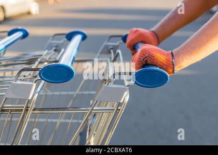 Mano dell'uomo, portare il carrello vuoto all'esterno del negozio sul via Foto Stock