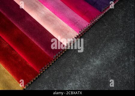 Campioni di velluto in sfumature di rosso e rosa su un tavolo in pietra scura con spazio per la copia Foto Stock
