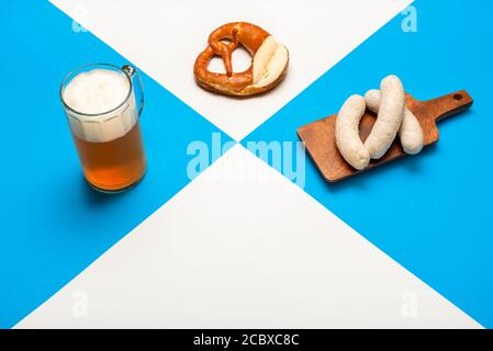 Poster Oktoberfest con birra non filtrata, salsiccia bianca e pretzel su sfondo bianco e blu. Tradizionale pasto bavarese. Cibo tedesco. Pinta di birra Foto Stock