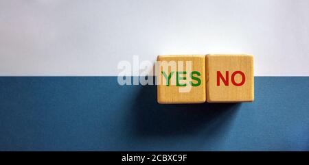 Cubetti di legno con parole 'sì, no' su sfondo bianco e blu di carta, spazio di copia. Concetto aziendale. Foto Stock