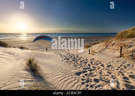 uomo in parapendio sulla spiaggia al tramonto dal mare in estate Foto Stock