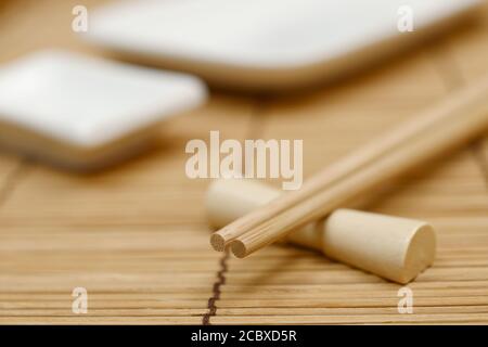 chopsticks giapponesi sullo stand, stuoia di bambù e piatti di sushi Foto Stock