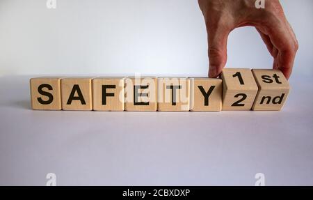 La mano trasforma un cubo e cambia l'espressione "sicurezza secondo" in "sicurezza prima". Splendido sfondo bianco, spazio per la copia. Concetto aziendale. Foto Stock