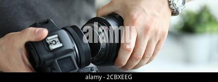 Mani maschili che indossano l'obiettivo professionale della fotocamera digitale moderna Foto Stock