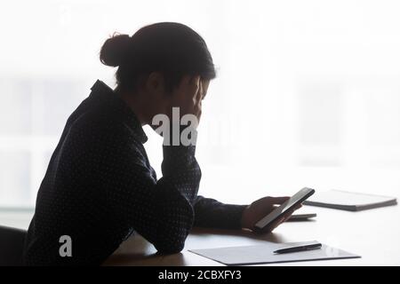 Infelice donna indiana che ha problemi con il dispositivo elettronico in ufficio. Foto Stock