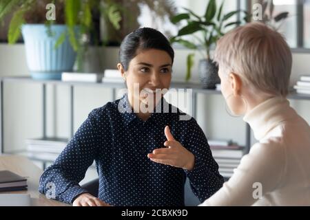 Due giovani dipendenti multirazziali discutono di problemi di lavoro. Foto Stock