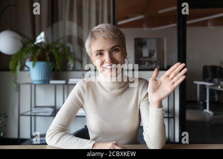Web camera vista sorridente giovane bionda businesswoman sventolando Ciao. Foto Stock