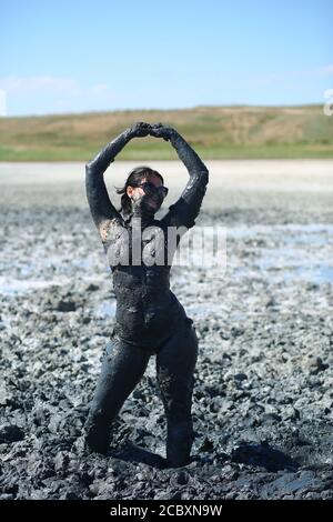 Ritratto di una giovane donna felice che posa con un fango curativo sul suo corpo. Terapia naturale dell'argilla medicinale. Lago di Syvash, Ucraina Foto Stock