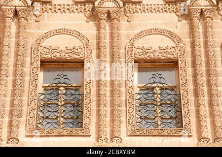 Le finestre e l'esterno di un antico palazzo in pietra nell'antica città cristiana di Midyat, nella regione orientale dell'Anatolia, nella Turchia sudorientale. Foto Stock