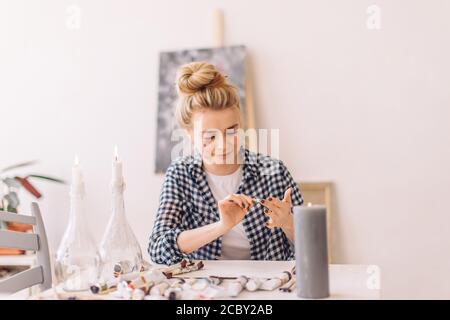 artista femminile con faccia sporca seduto al tavolo in studio d'arte. primo piano foto. Foto Stock