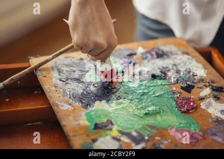 l'artista maschile tiene tubi di vernice acrilica, mescola colori per la pittura su palette . Arte, creatività, concetto hobby. Primo piano foto ritagliata Foto Stock