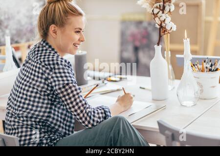 donna bionda positiva impressionante che gode il disegno a casa, felicità, passatempo, lavoro, professione Foto Stock