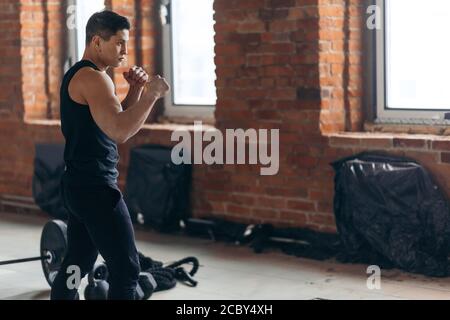 pugile giovane e motivato con pugno clenching in posizione di difesa. primo piano vista laterale foto. sport di combattimento Foto Stock