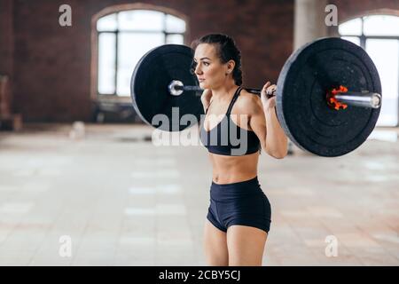 bella donna che fa esercizio con il carico di barbell sulla parte posteriore, primo piano vista laterale foto. stile di vita, assistenza sanitaria Foto Stock