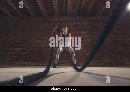 Il duro lavoro di crossfit femmina istruttore dimostra che la formazione delle corde sono molto allenamento dinamico che accelera l'atleta di impulso mentre il rafforzamento del suo Foto Stock