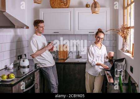 bella donna caucasica lavoratrice alla freelance, lavora anche a casa usando il laptop. marito la sostiene e passa la mattina accanto a lei. Foto Stock