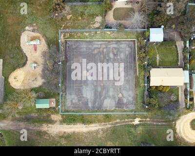 Vista aerea del campo da tennis in ambiente suburbano che mostra linee e marcature del campo da tennis, capannoni e parco giochi. Foto Stock