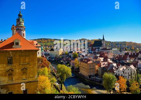 La vista della città di Cesky Krumlov nel tardo pomeriggio, cielo blu chiaro, in contrasto con il giallo delle foglie e l'arancione della città vecchia Foto Stock