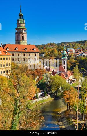 La vista della città di Cesky Krumlov nel tardo pomeriggio, cielo blu chiaro, in contrasto con il giallo delle foglie e l'arancione della città vecchia Foto Stock