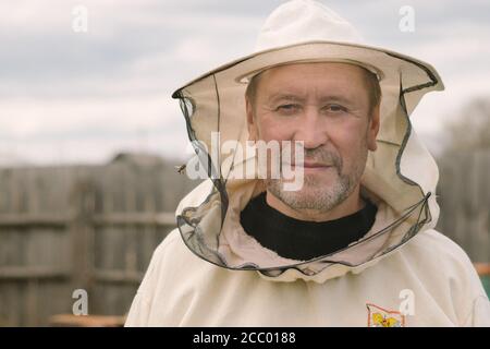 Aromashevsky Russia maggio 24 2018: Ritratto di un apicoltore in maschera con un'ape Foto Stock