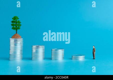 Concetto di business in miniatura - un anziano in piedi su una pila di monete scala per fare gli investimenti finanziari Foto Stock