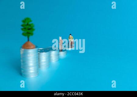 Concetto di business in miniatura - un anziano in piedi su una pila di monete scala per fare gli investimenti finanziari Foto Stock