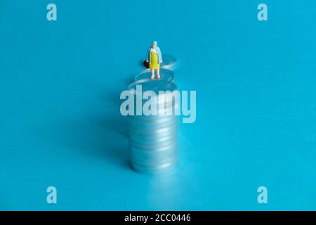 Concetto di business in miniatura - un anziano in piedi su una pila di monete scala per fare gli investimenti finanziari Foto Stock