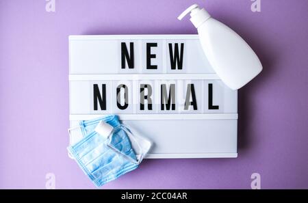 Scatola luminosa con testo NUOVA MASCHERA protettiva NORMALE e igienizzatore. Ritorno a scuola. Distanza sociale. Concetto di quarantena scolastica. Foto Stock