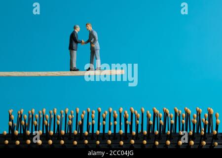 Concetto di business in miniatura - due imprenditori fanno strategia di partnership per trasferimento della gestione del rischio Foto Stock