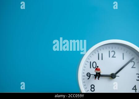 Miniatura persone per il concetto di tempo di lettura del mattino - giovane uomo posti a sedere sopra in senso orario leggendo un libro Foto Stock