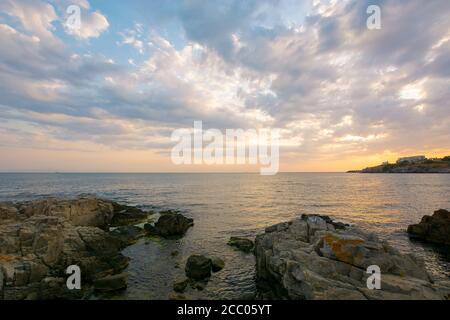 tramonto sulla costa del mare nero. splendido paesaggio spettacolare con rocce sulla spiaggia di ghiaia sotto un cielo nuvoloso. vacanze in velluto Foto Stock