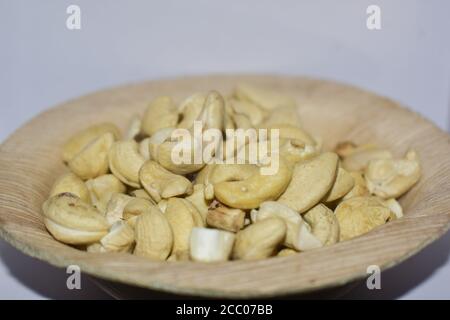 Cashews tenuti in una tazza di legno con fondo bianco puro Foto Stock