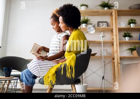 Libro di lettura della bambina con la madre a casa Foto Stock