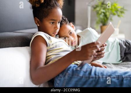 Dei bambini felici havig divertimento e utilizzando dispositivi di tecnologia Foto Stock