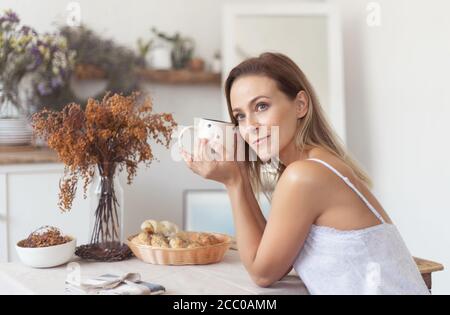 Giovane bella donna che ha fatto colazione al mattino in cucina. Foto Stock