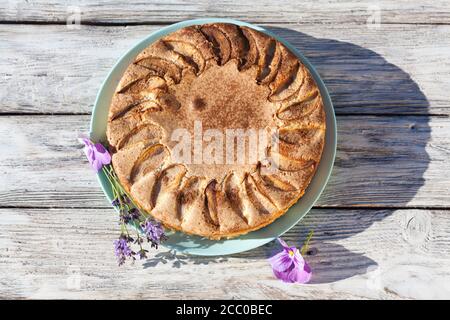 Pezzo di torta di mele con fiori su tavola rustica di legno Foto Stock