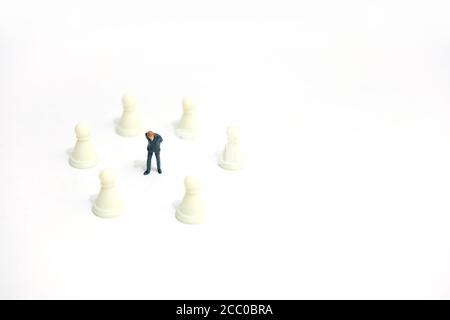 Concetto di strategia commerciale in miniatura - uomo d'affari in piedi tra il pezzo di scacchi Foto Stock