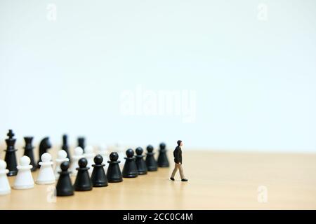 Concetto strategico di persone in miniatura - giovani uomini d'affari si muovono camminando dentro fronte della pedina degli scacchi Foto Stock